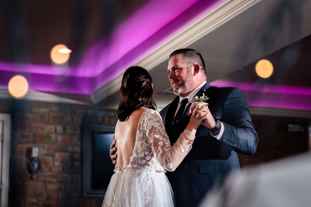 Wedding reception dance floor scene with purple uplighting and romantic atmosphere.