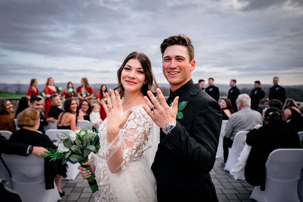 Wedding couple sharing their first dance surrounded by guests on an outdoor terrace.