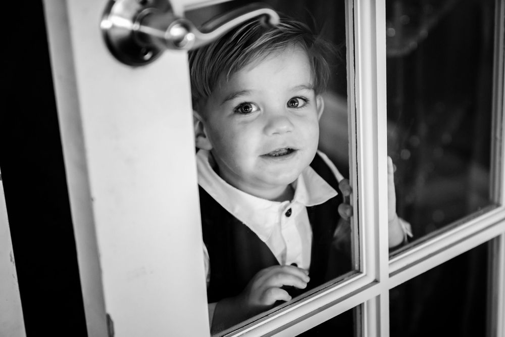 Black and white photo of children looking through window panes.