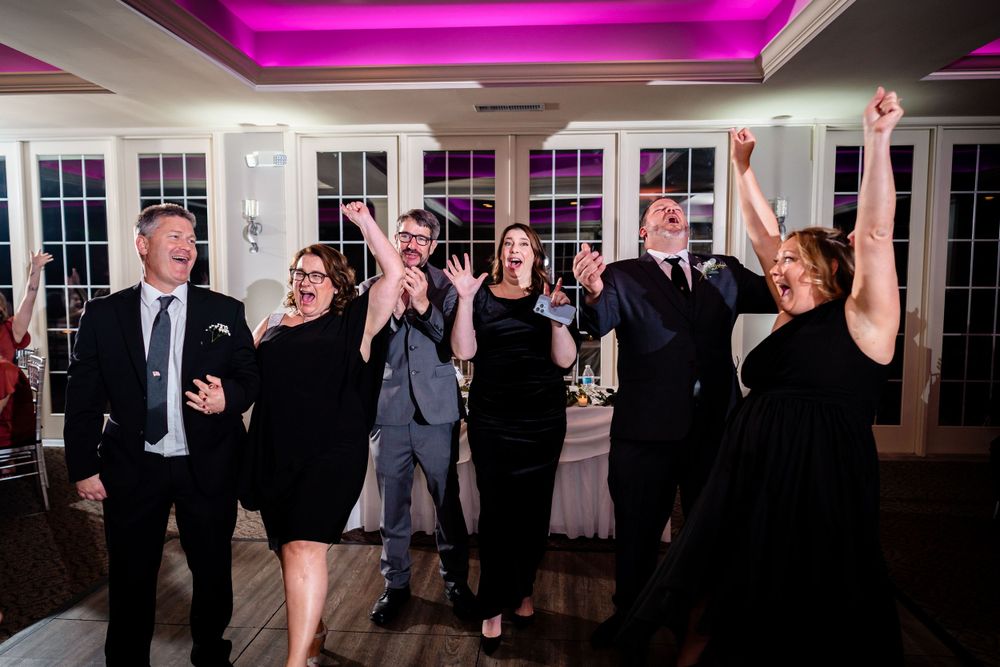 Wedding reception party with purple uplighting and guests dancing.