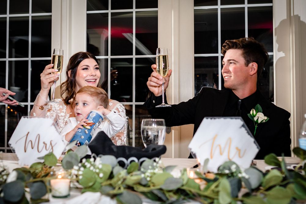Wedding reception table decorated with greenery and candles in an elegant windowed room.