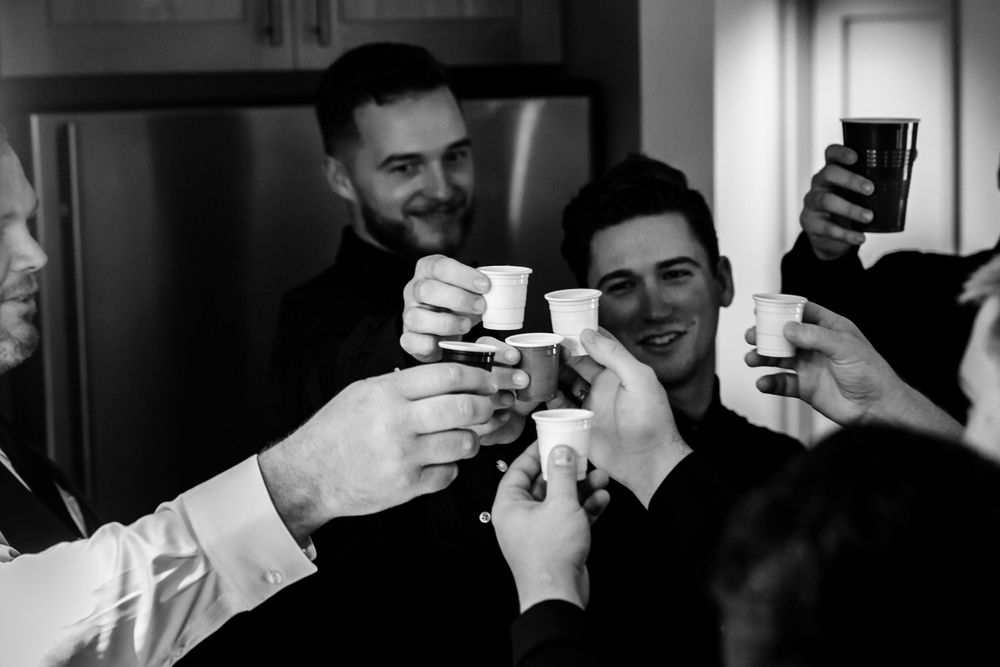 Groomsmen raise their glasses in a celebratory toast at a wedding reception.