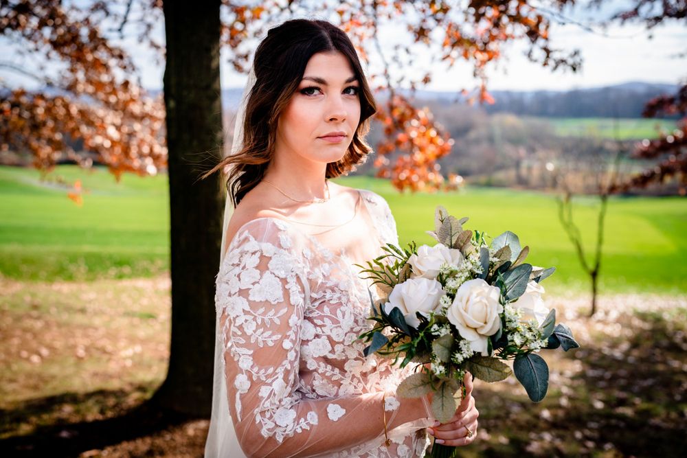 A bridal portrait in an autumn setting with fall foliage and white floral bouquet.