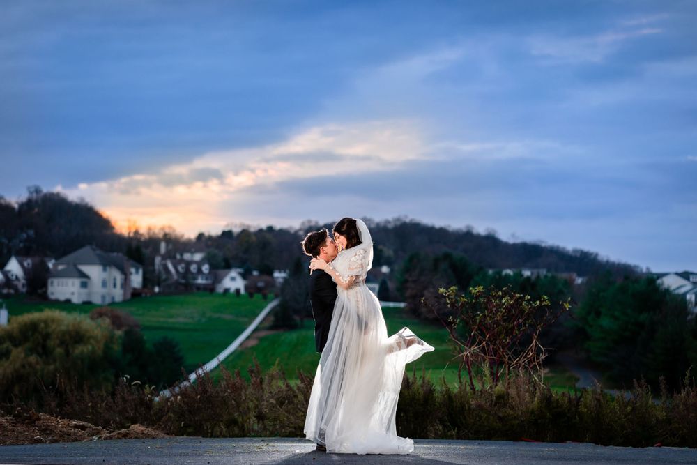 Dramatic wedding portraits taken against a scenic countryside backdrop at dusk.