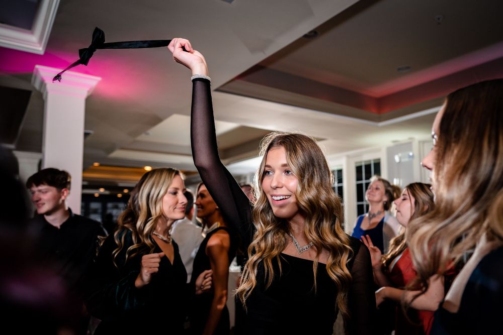 Partygoers celebrating on a dance floor under pink and purple lighting.