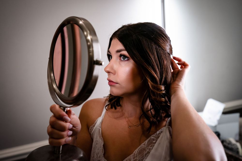 Wedding preparation scene with mirror reflection and soft natural lighting.