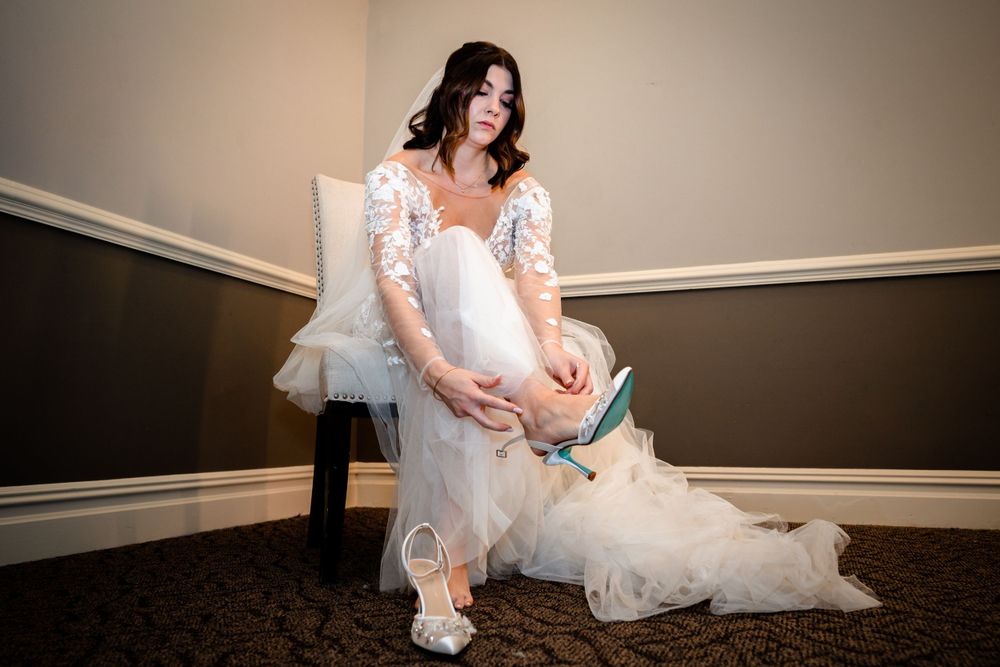 A bride in a white dress sits elegantly in an indoor venue.
