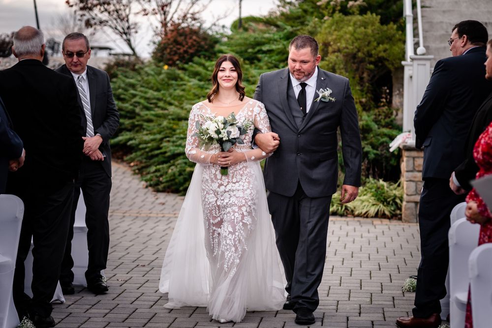 Wedding party walking along stone pathway during outdoor celebration.