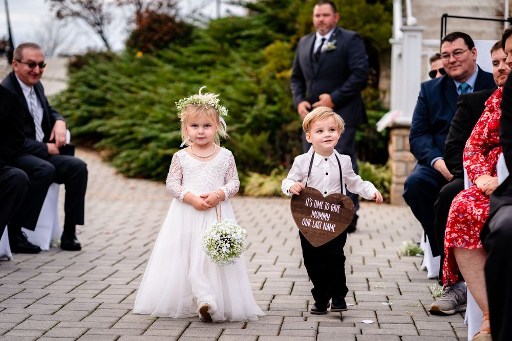 Wedding processional on stone pathway with flower girls in white dresses.