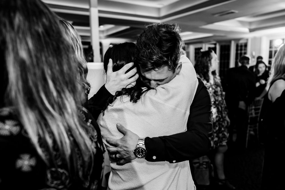 Guests dancing and mingling at an indoor reception with mood lighting.