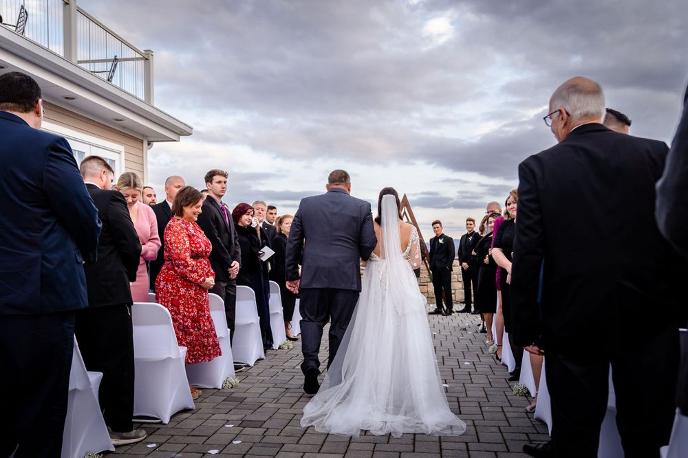 Wedding ceremony gathering on stone patio under cloudy skies.
