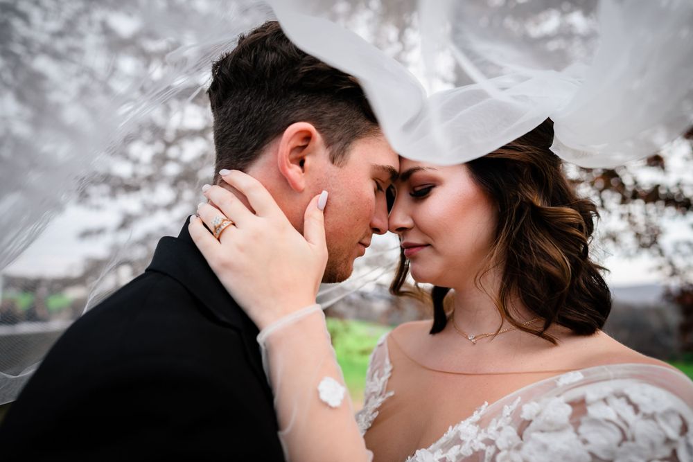 Candid wedding portrait showing tender moment between couple outdoors.