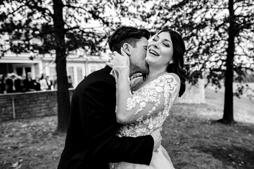 Romantic wedding portrait with couple embracing under tree branches.