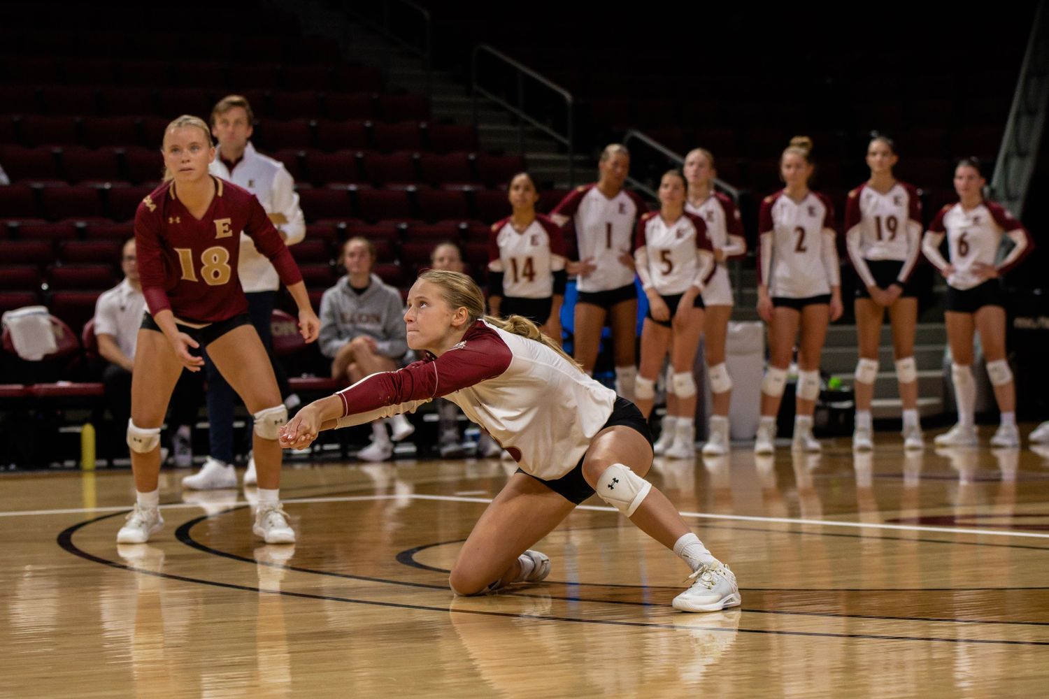 Volleyball players diving for the ball during an intense indoor match.