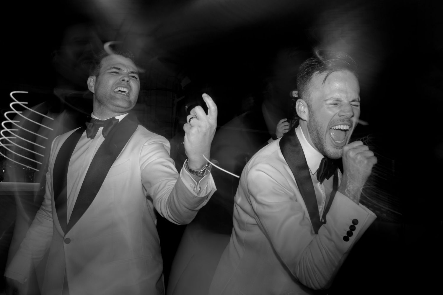 grooms dancing at the reception in black and white wearing tuxes