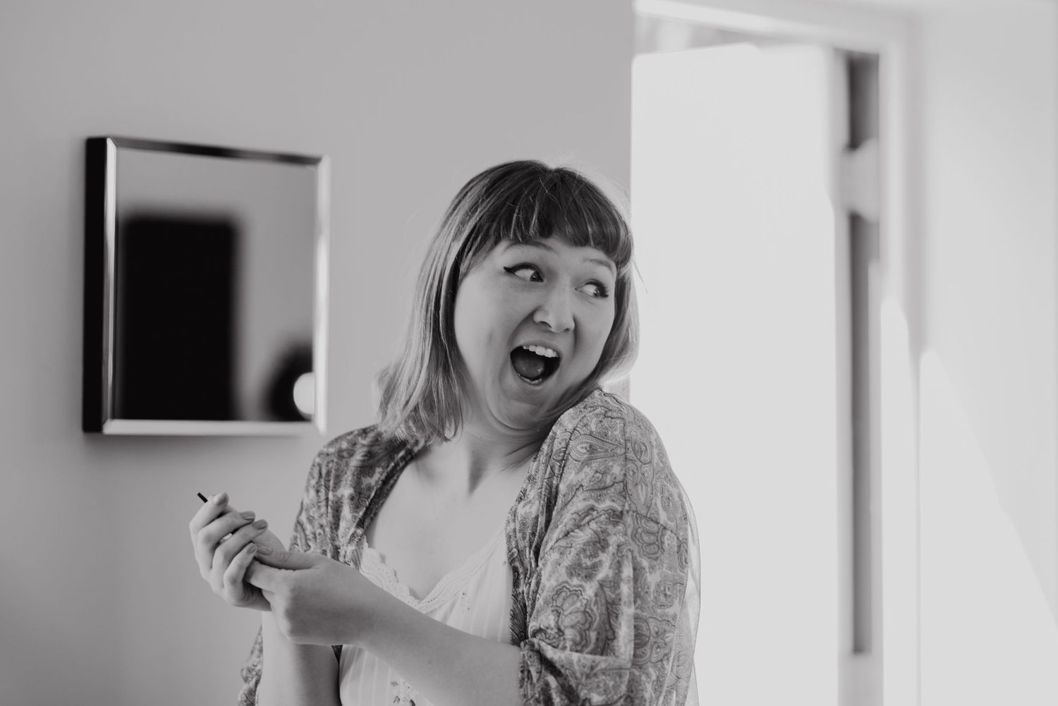 A candid moment of joyful laughter captured in black and white in a minimalist interior setting.