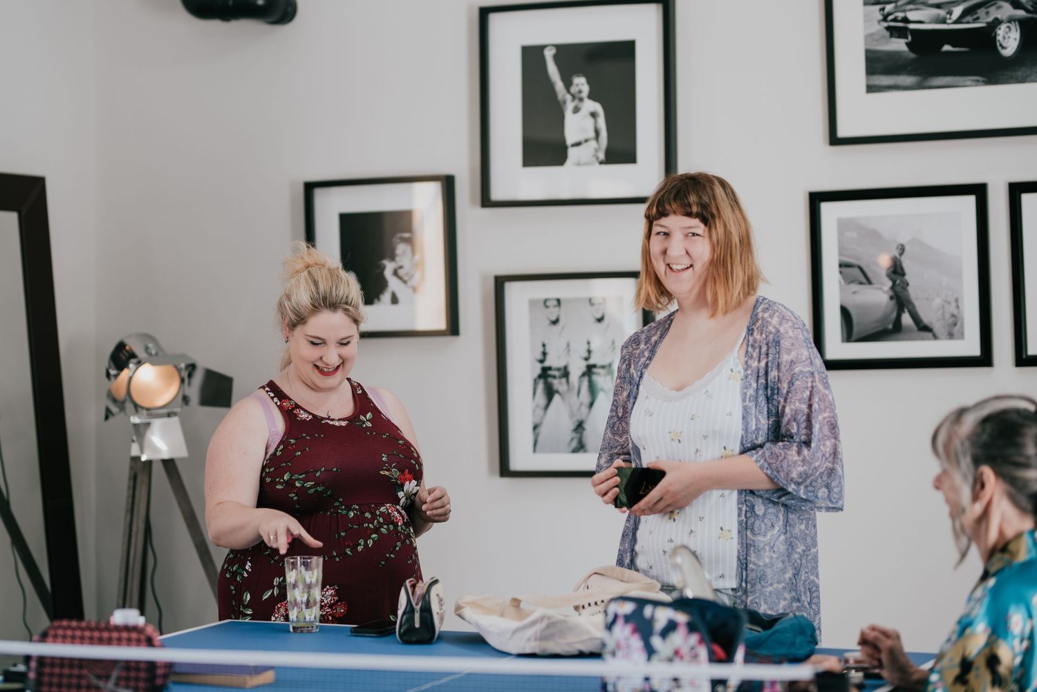 Wedding preparation scene with people getting ready amongst framed wall photographs.