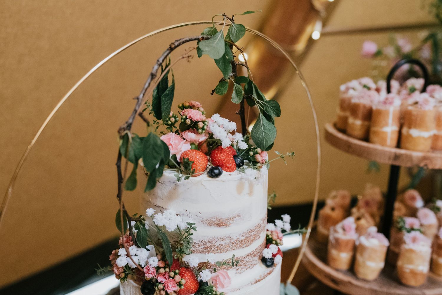 Rustic wedding cake with greenery arch and dessert table display.
