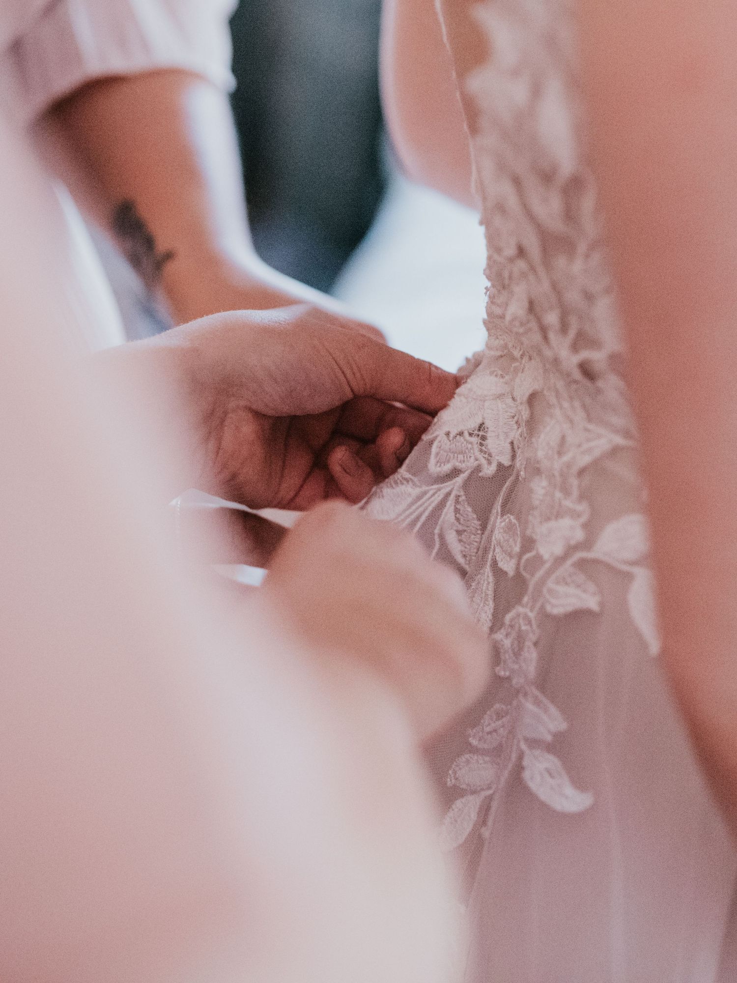 Close-up detail of delicate lace and embroidery work on a white wedding dress.