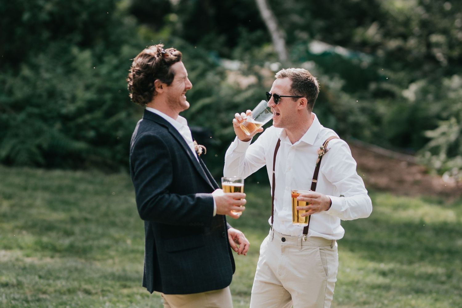 Two guests enjoying drinks and conversation at an outdoor wedding reception.