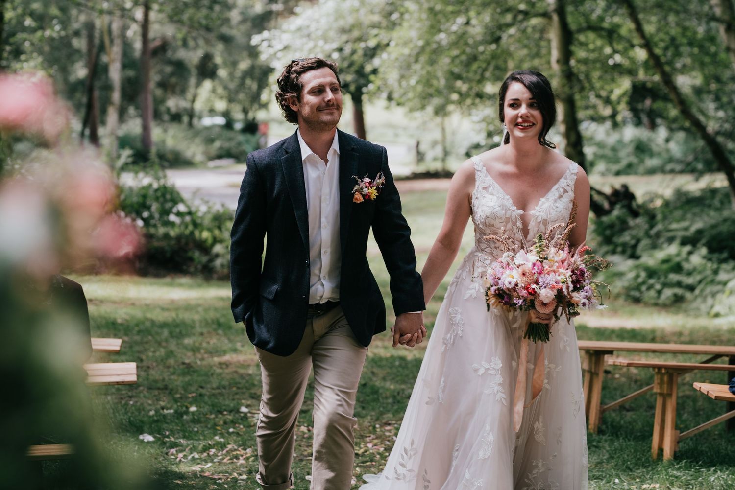 A couple strolling together through a garden path during their wedding celebration.