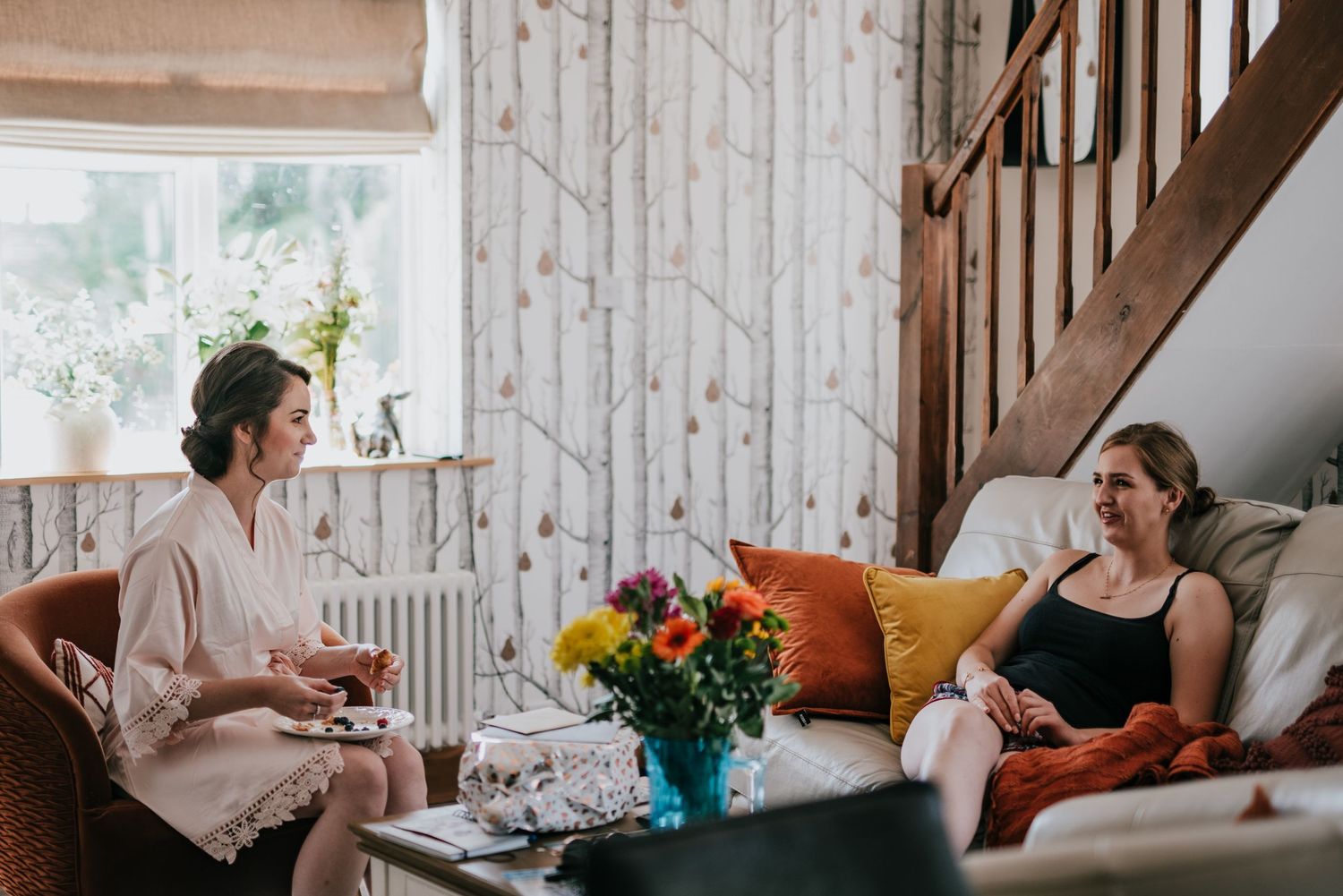 A cozy living room scene with floral wallpaper and a bright bouquet on the coffee table.