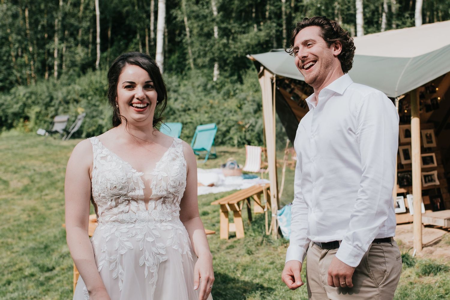 Candid moment of joyful laughter at an outdoor wedding with tent in background.