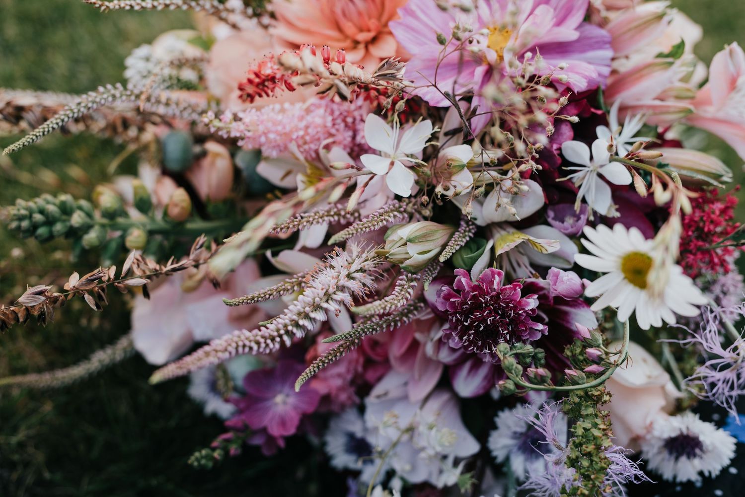 Close-up of a romantic wedding bouquet with pink and purple flowers and delicate greenery.
