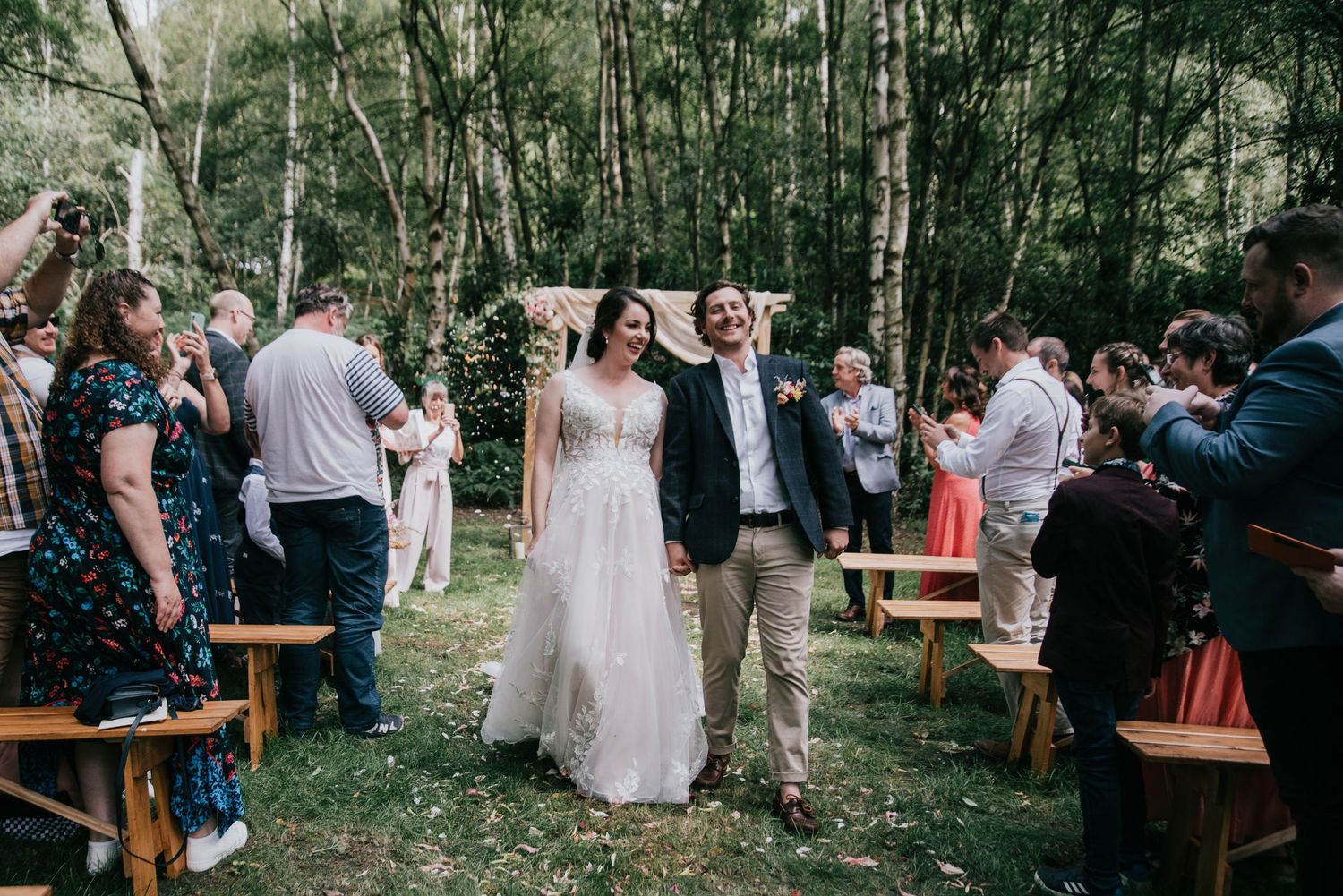 Newlyweds celebrate with guests during recessional at outdoor forest wedding.