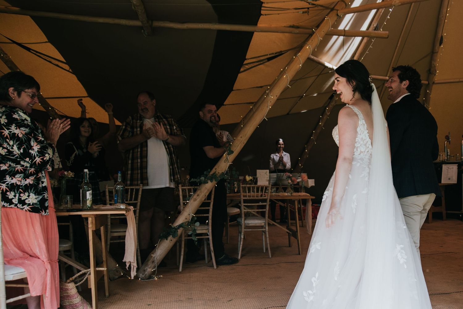 Wedding celebration inside a rustic tent venue with guests mingling.