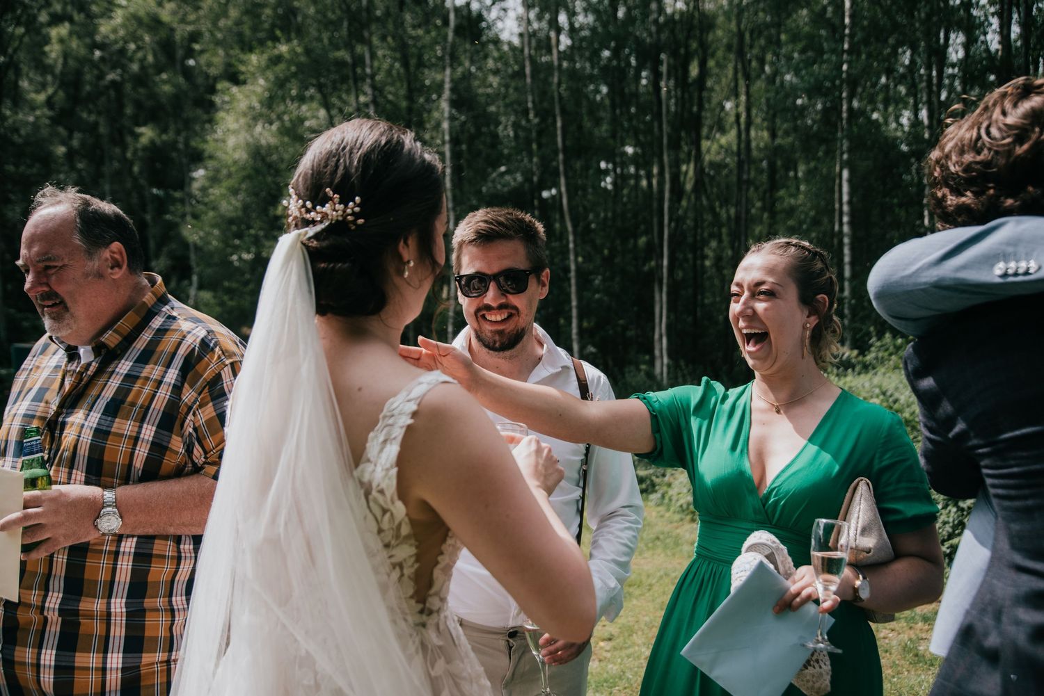 Wedding guests mingle and celebrate at outdoor forest reception.