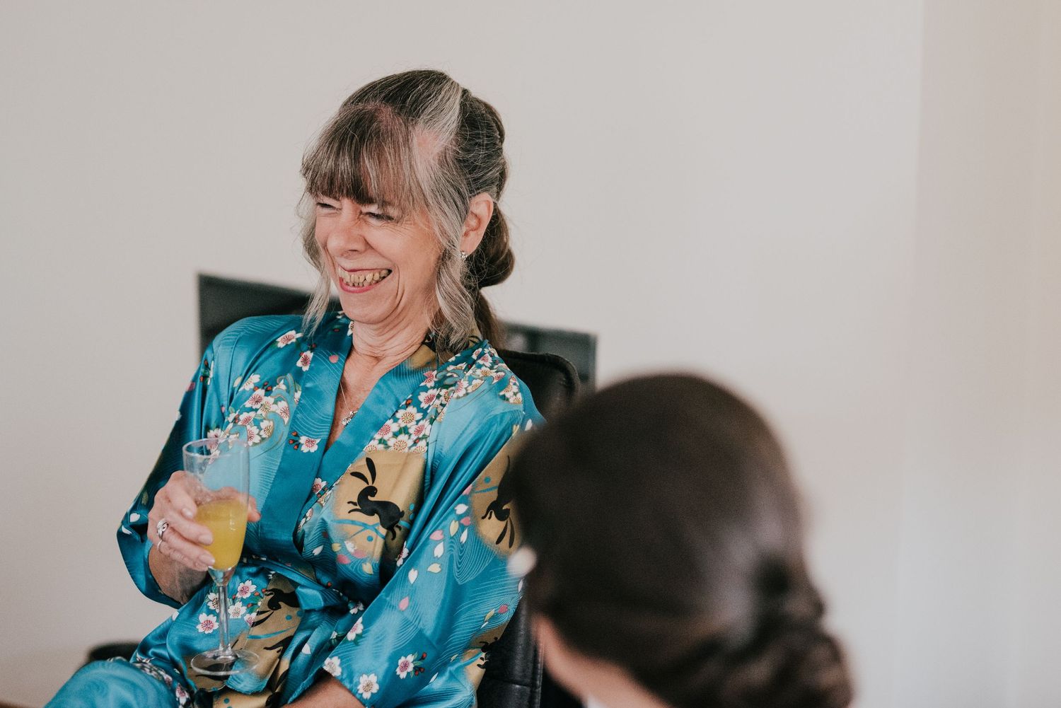 A cheerful moment shared over drinks in a bright indoor setting with a blue floral robe.
