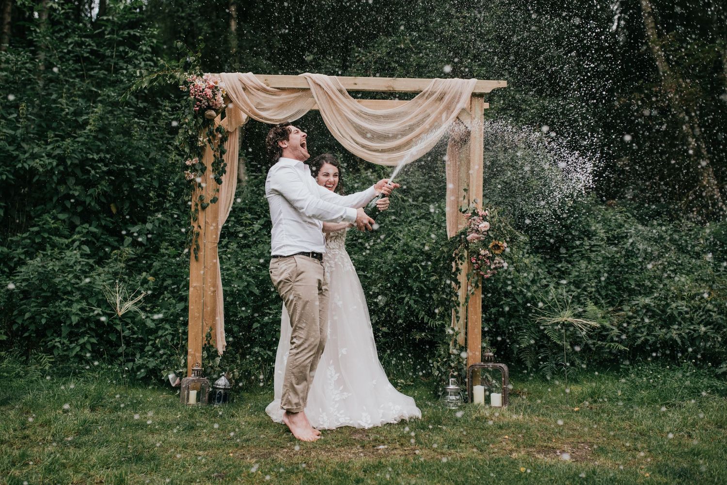 A dancing couple spins under a wooden arch during their outdoor wedding celebration.