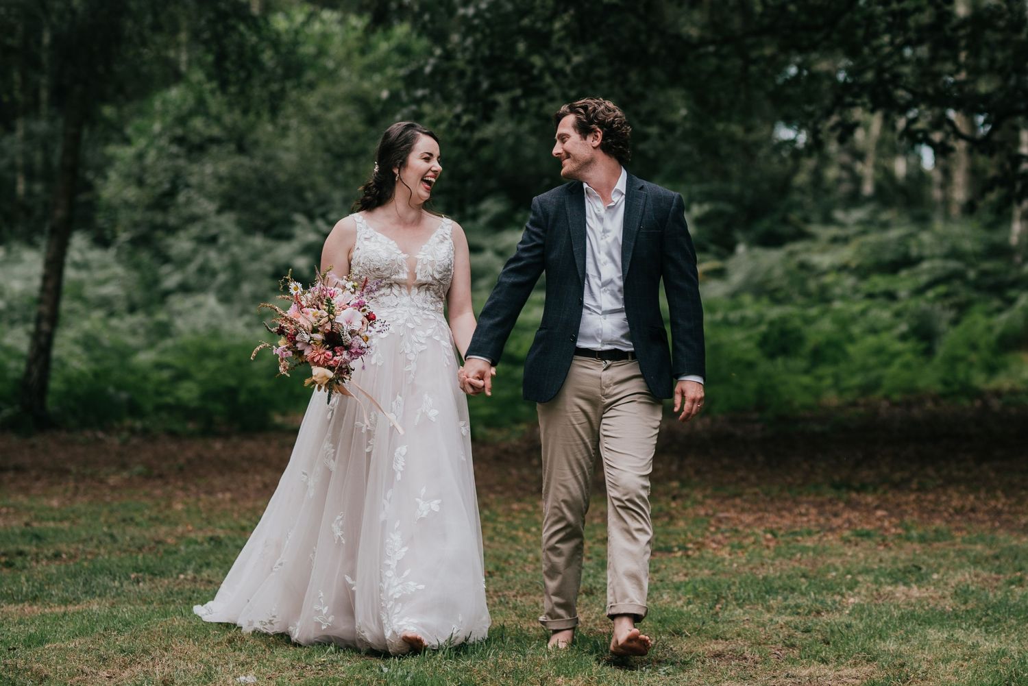 A couple shares a romantic moment while walking together outdoors in wedding attire.