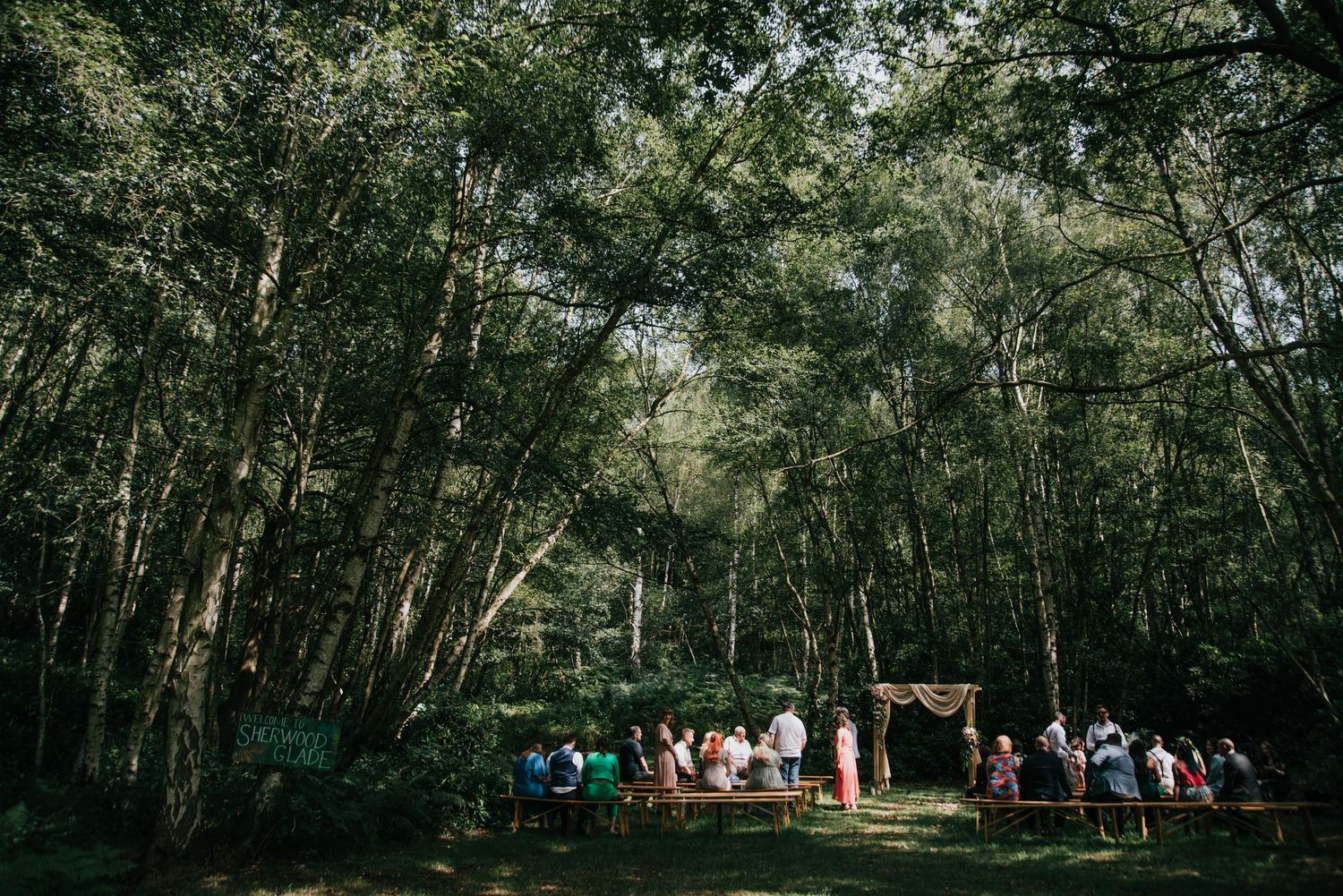 Wide shot of a wedding ceremony setup in a serene forest clearing.