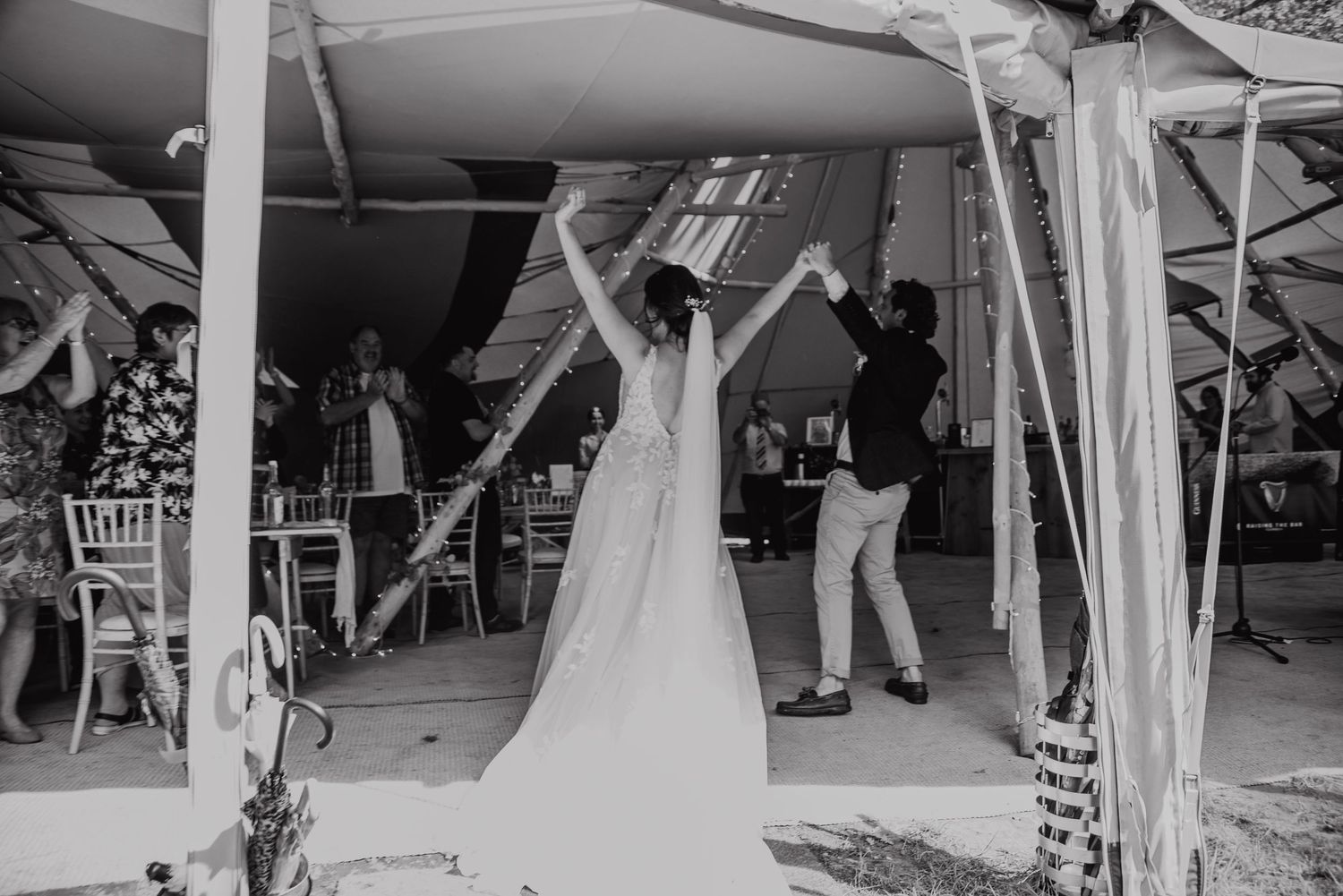 A black and white photo of dancing celebrations under a covered outdoor venue.
