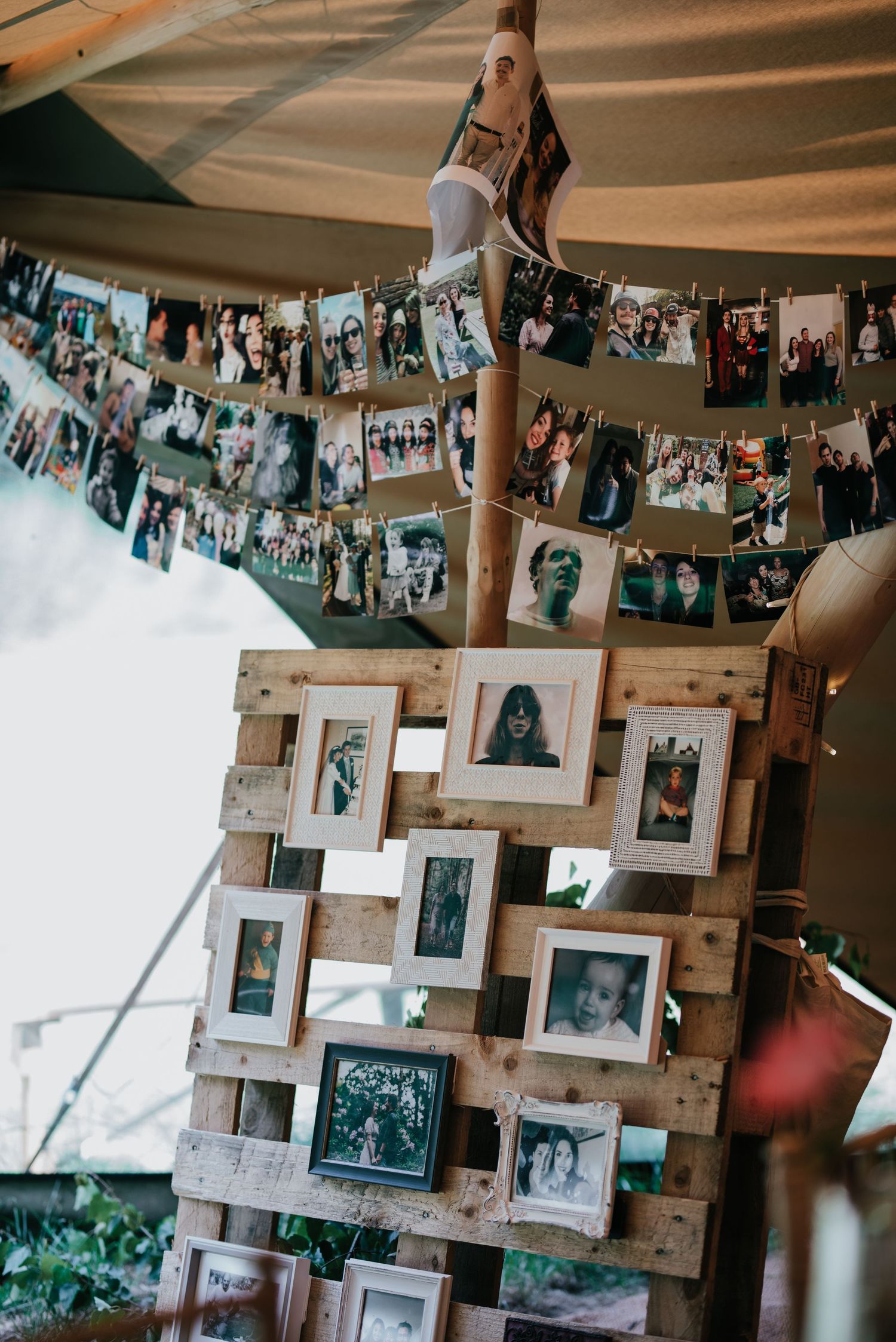 A rustic photo display setup with polaroid pictures hung on strings and wooden pallets adorned with framed photographs.