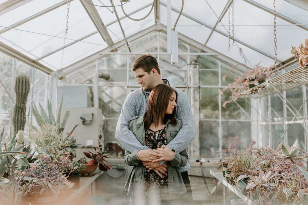 Romantic greenhouse engagement session surrounded by delicate spring blossoms.