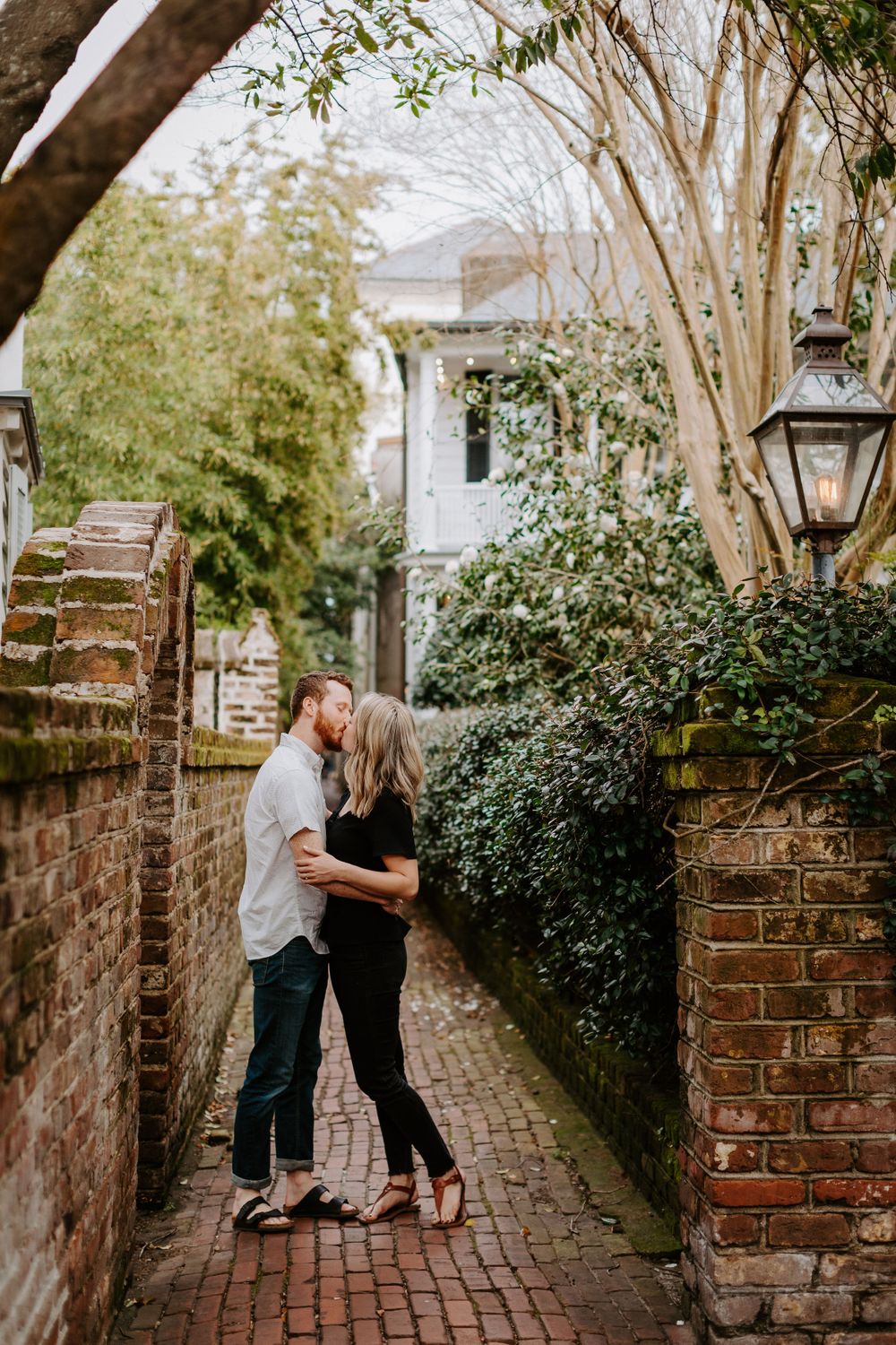 Romantic moment on brick-lined Charleston alley with historic architecture.