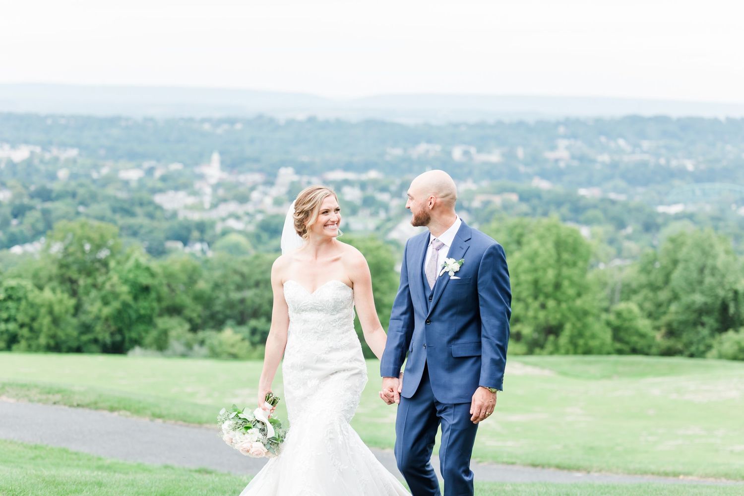 A scenic hilltop wedding moment overlooking a distant town and rolling countryside.