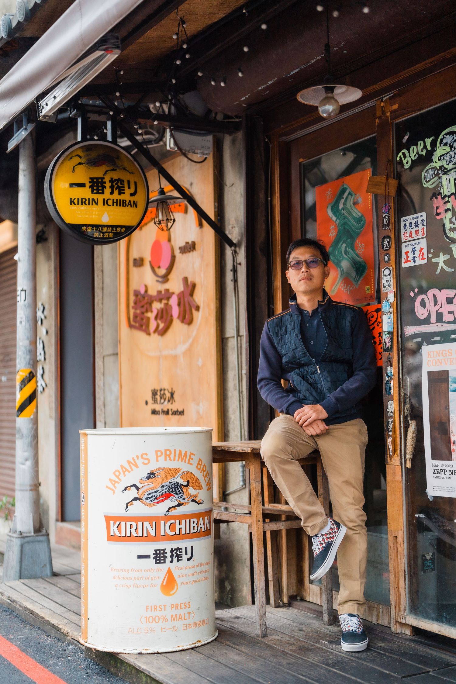 Person in navy jacket leaning against entrance of Japanese restaurant with vintage decor.