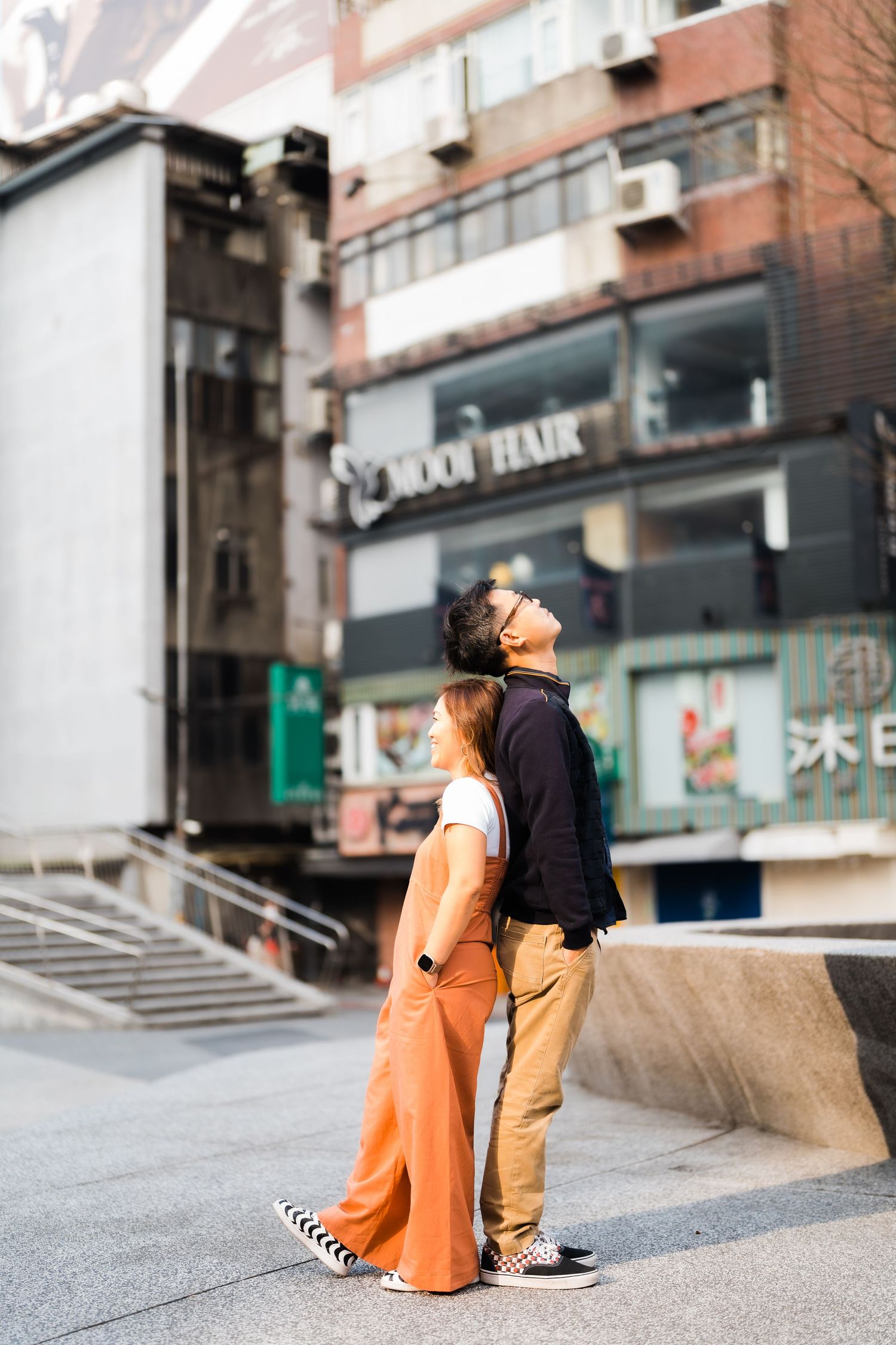 Two people looking up at urban buildings while standing together on city street.