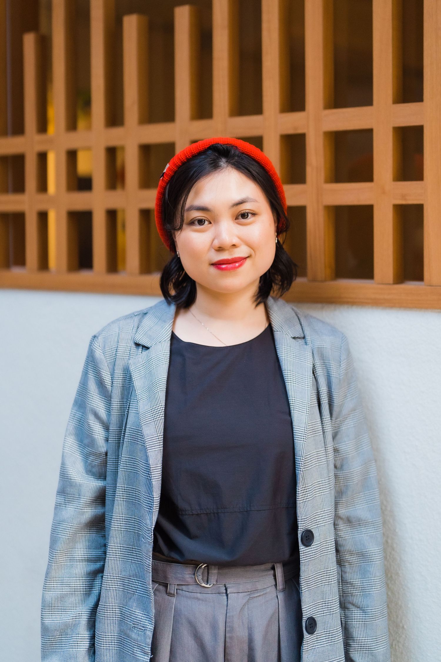 Casual portrait against wooden lattice wall wearing red headband and gray blazer.