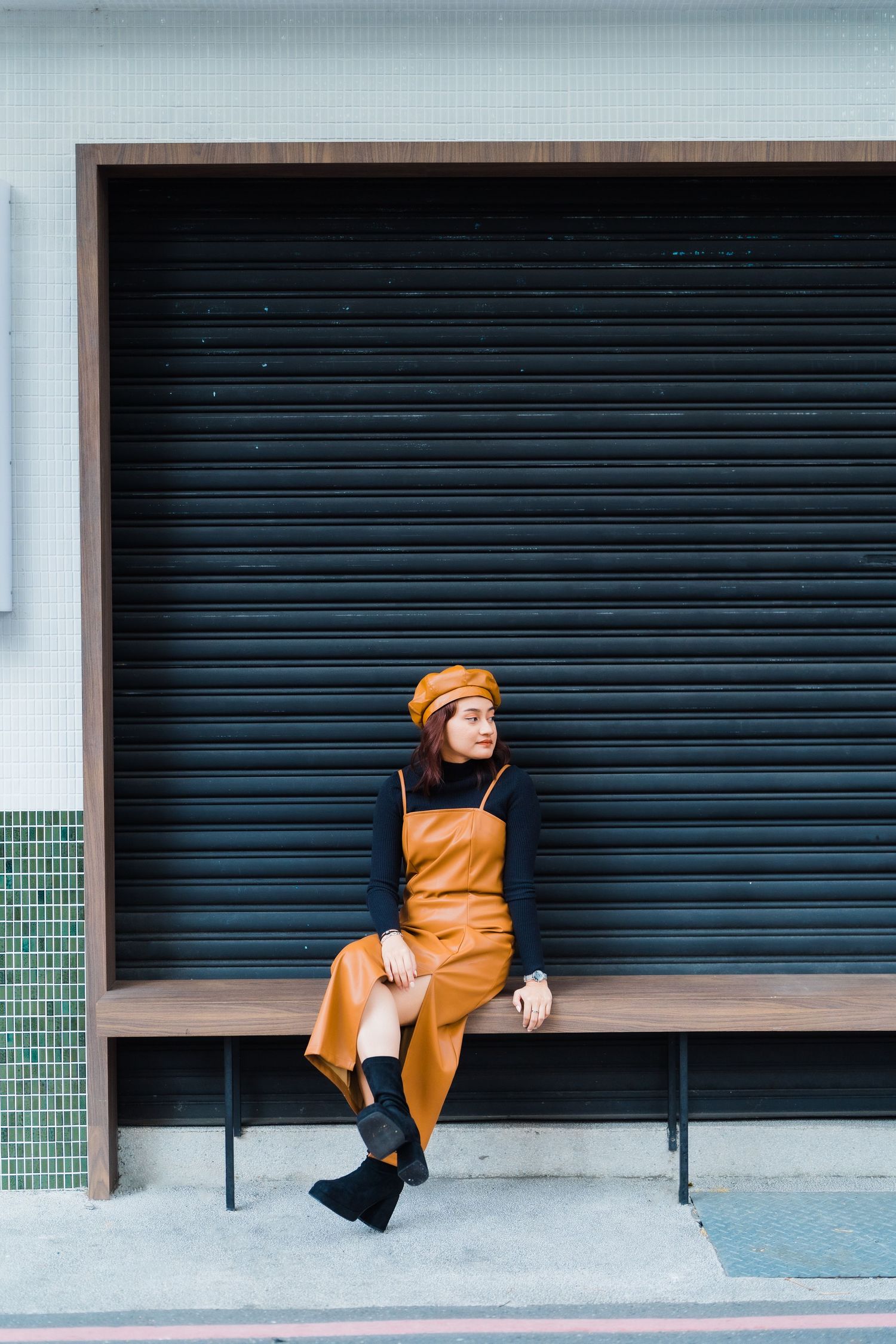 Person in mustard yellow overalls sits on ledge against industrial garage door.