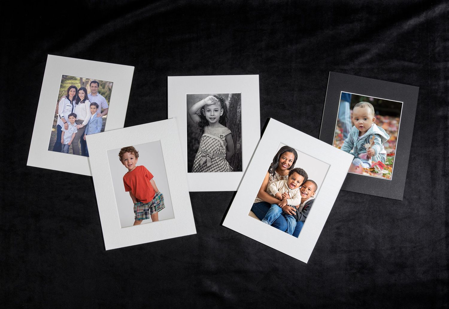 Five matted portrait photos of families and children arranged on dark velvet background.