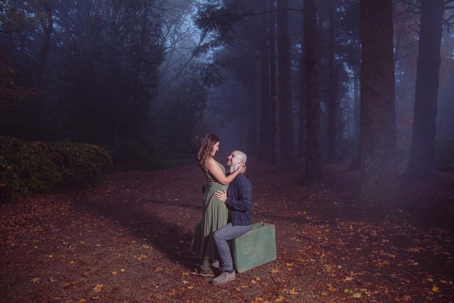 A romantic photo series in a misty forest with moody lighting and fallen leaves.