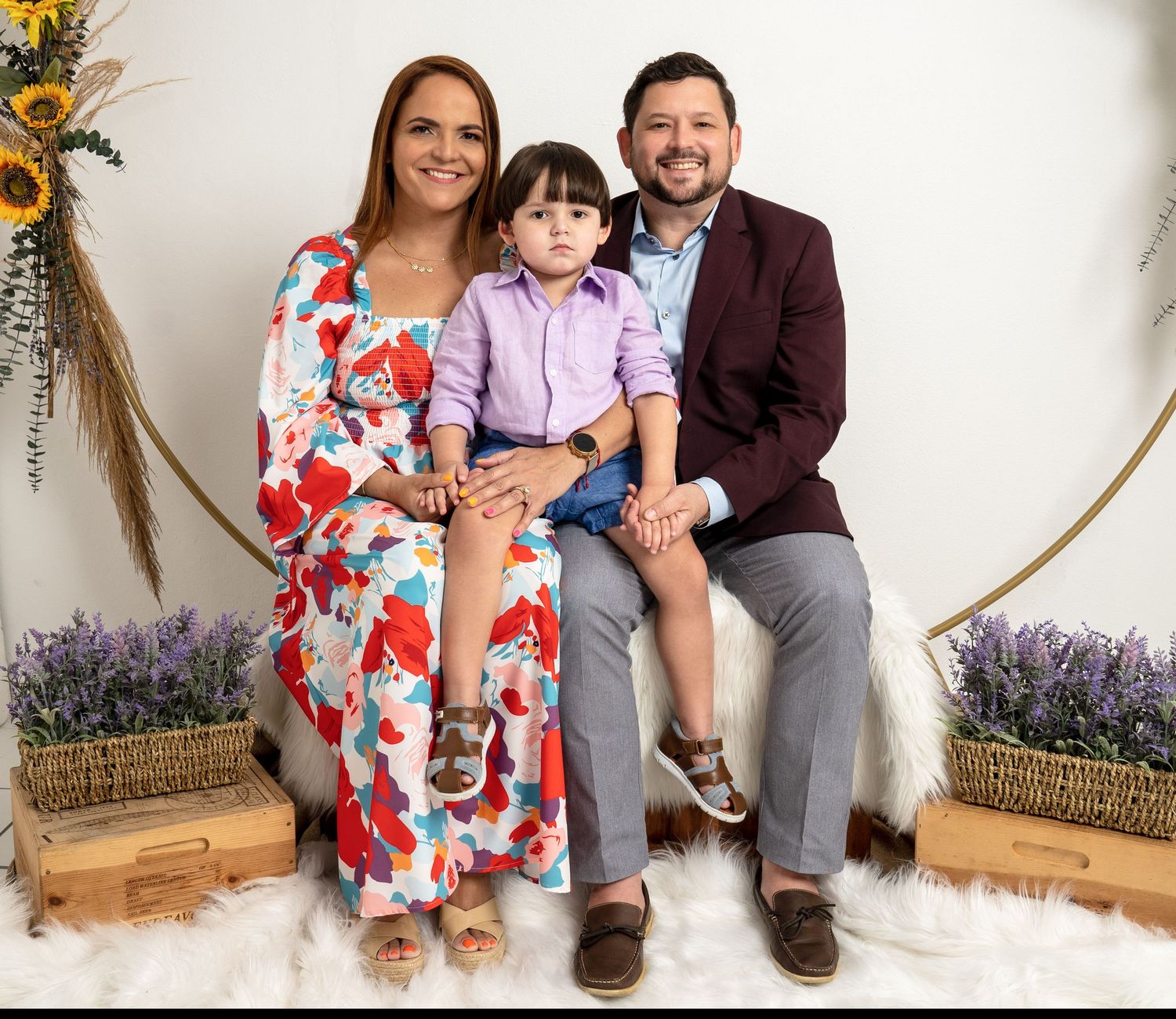 A family poses together in a studio setting with lavender and sunflower decorations.