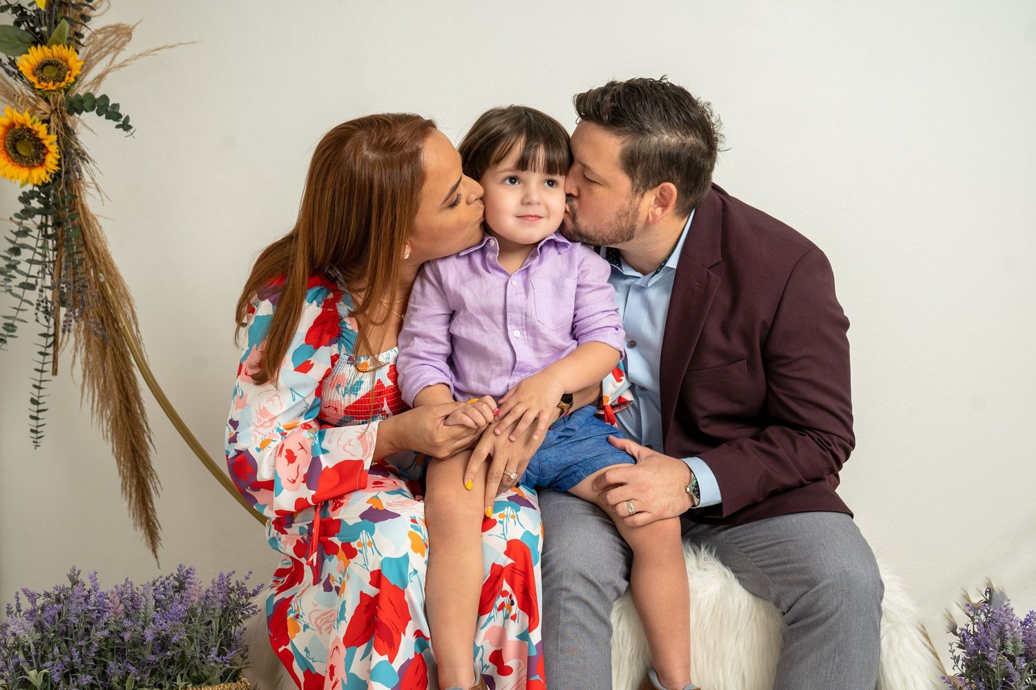A family shares an intimate moment in a portrait studio with floral decorations.