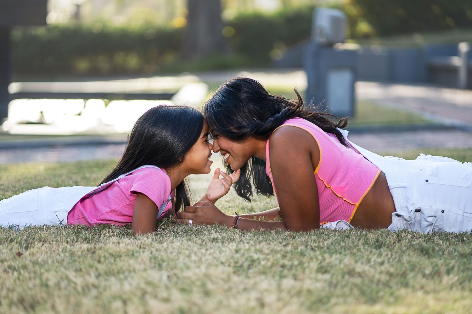 Sweet candid moment on grass lawn in matching pink outfits.