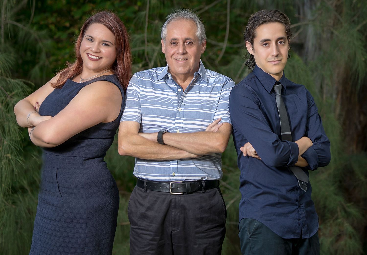 Three generations pose together outdoors in formal attire.